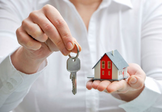 Woman giving model house and keys.